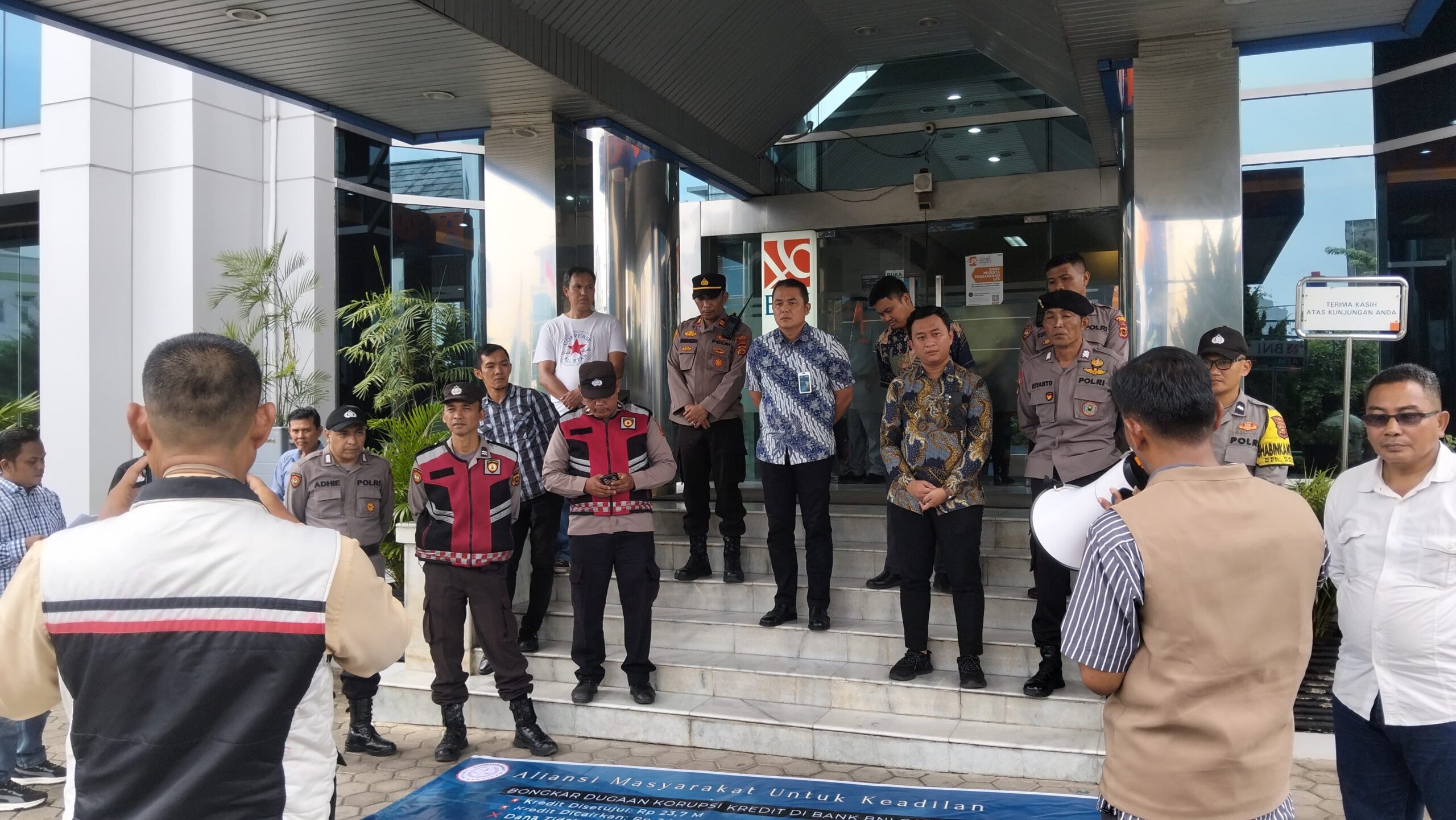 Aliansi Masyarakat untuk Keadilan (AMUK) membentangkan spanduk protes di depan BNI Jambi terkait dugaan penyaluran kredit bermasalah.